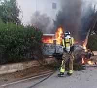 Un bombero del CEIS interviene para apagar un incendio en un veh&iacute;culo tras un accidente.