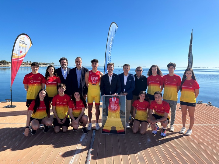 Autoridades deportivas y federativas y atletas posan con las equipaciones frente al Mar Menor.