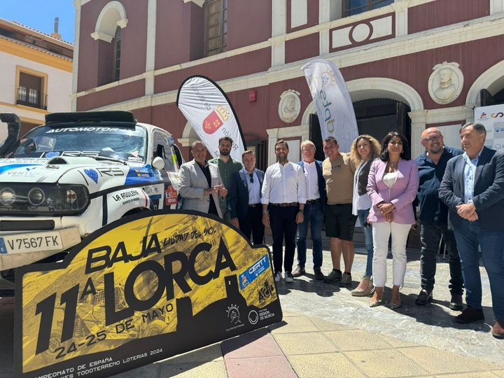 Autoridades y miembros de la organización, con uno de los vehículos, en el acto de presentación