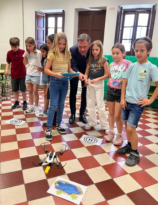 El consejero de Presidencia, Portavocía y Acción Exterior, Marcos Ortuño, en compañía de otros menores, observa el vuelo de un dron dirigido por una alumna del taller de robótica.