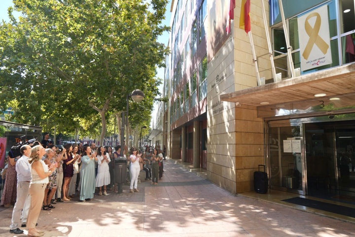 La consejera de Política Social, Familias e Igualdad, Conchita Ruiz, junto con el presidente de AFACMUR, Francisco Palazón, durante el despliegue de un lazo dorado en la fachada de la consejería con motivo de la campaña de concienciación del cáncer infantil (1)